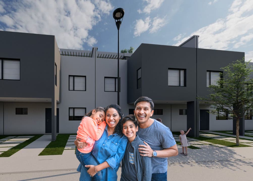 Familia mexicana de dos papas y su hijo e hija sonriendo frente a su nueva casa en Tepeji